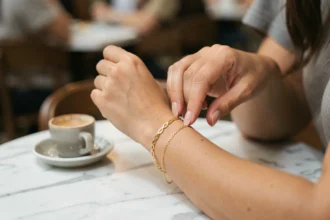 Femme portant un bracelet femme en or délicat ajusté sur son poignet dans un café au décor en marbre