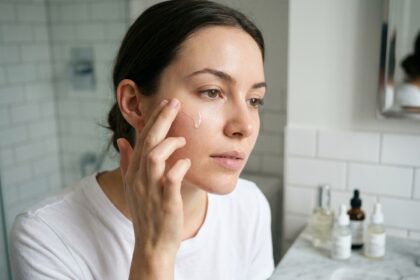 Jeune femme appliquant un sérum visage sur peau grasse dans une salle de bain minimaliste